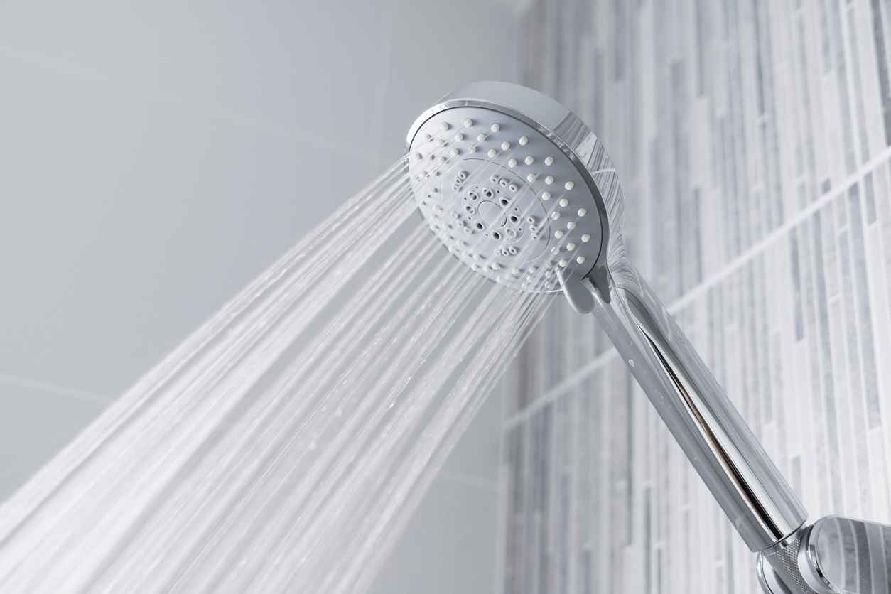 A clean showerhead in the bathroom with water flowing